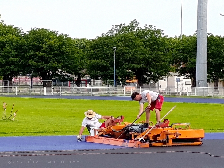 Chantier de la piste d'athlétisme de Sotteville-lès-Rouen : coulage et étalage du nouveau revêtement bleu.